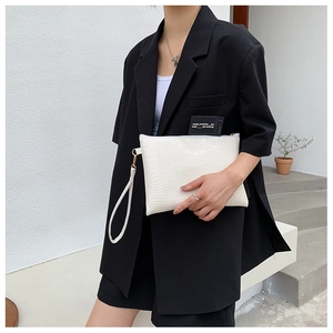 Pochette bianca con stampa coccodrillo portata da modella con blazer nero
