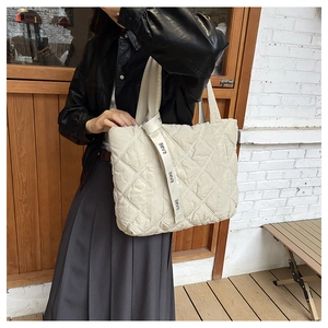 Minimalist beige quilted cotton tote bag with diamond stitching shown on a fashion model