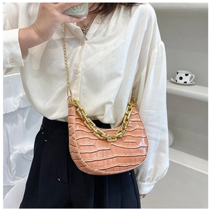 Detail of pink faux crocodile crescent bag with golden chain and metallic shoulder strap