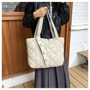 Detail of cream quilted tote bag featuring EARE printed strap and soft puffer texture