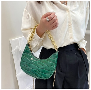 Detail of green crocodile pattern crescent bag with dual gold chain straps and glossy finish