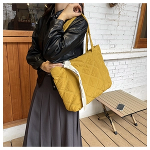 Detail of yellow quilted tote bag featuring a white decorative strap with EARP lettering