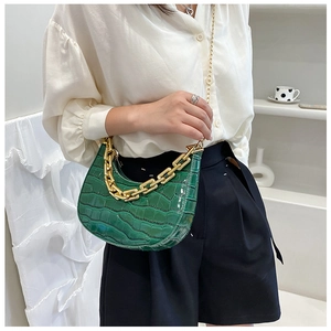 Detail of emerald green crocodile pattern crescent bag with bold gold chain and strap