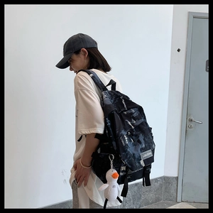 Détail d'un sac à dos avec imprimé artistique et porte-clés canard blanc en peluche