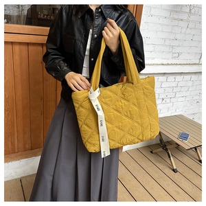 Detail of yellow quilted tote bag with EARE ribbon strap and soft diamond stitching pattern