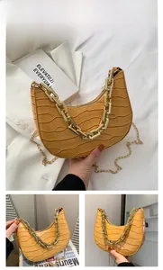 Detail of yellow crocodile pattern crescent bag with chunky gold chain strap