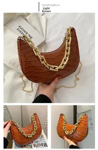 Detail of light brown crocodile pattern crescent bag with chunky gold chain handles