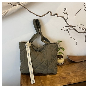 Close-up of army green quilted tote bag with diamond stitching and EARE letter strap
