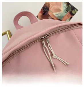Detailed macro view of smooth dual metal zippers with braided pullers on pink backpack