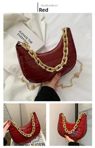 Detail of red crocodile pattern crescent bag with chunky gold chain strap and accessories