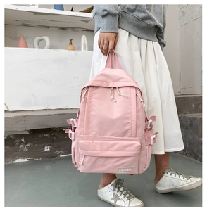 Close-up of pink nylon backpack showing white buckles and brand label detail