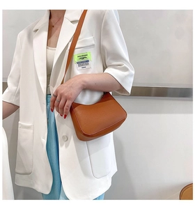 Close-up of caramel brown crescent moon underarm bag with smooth faux leather finish