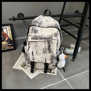 Détail du sac à dos en toile imprimé journal avec pendentif de canard en peluche blanc