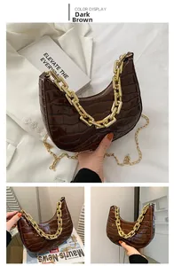 Detail of dark brown faux crocodile crescent bag with bold gold chain and glossy finish