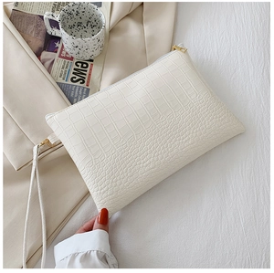 Dettaglio della pochette a busta crema con trama in pelle goffrata a coccodrillo di lusso