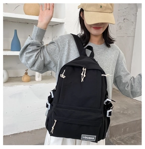 Detailed view of black student backpack with white buckle and zipper pulls on model