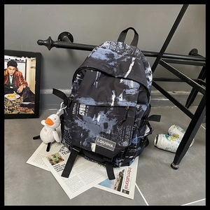 Détail du sac à dos noir avec imprimé éclaboussures bleues et breloque canard en peluche