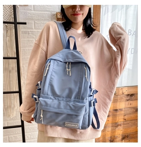 Detail of light blue waterproof nylon backpack with contrast zippers and brand logo tag