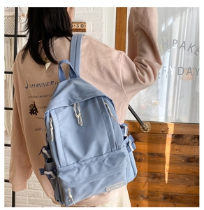 Rear view of a light blue nylon backpack with adjustable side straps and white buckles