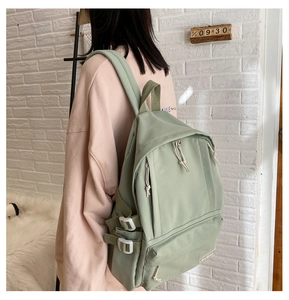 Detail of mint green canvas backpack featuring side buckles and large front pocket