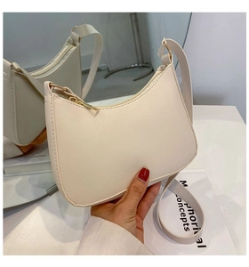 Detail of a minimalist cream hobo bag with gold zipper and adjustable shoulder strap