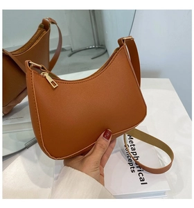 Close-up of brown PU leather shoulder bag featuring minimalist curve design and gold zipper