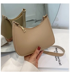 Detail of minimalist beige crescent shoulder bag with golden zipper and lychee grain leather