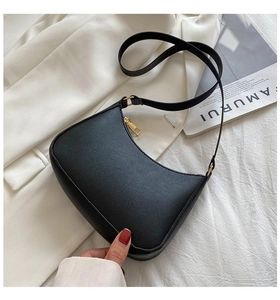 Detail shot of a minimalist black leather hobo bag with a premium golden metal zipper