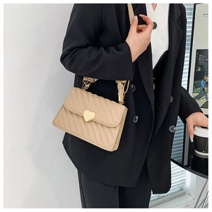 Detailaufnahme beigefarbene Falten-Schultertasche mit goldener Herzschnalle am Sakko