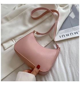 Detail view of pink pebbled leather hobo bag with sleek golden hardware on white fabric