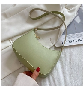 Close-up of light green half-moon bag featuring litchi grain texture and gold hardware