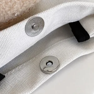 Nahaufnahme des silbernen Magnetverschlusses an der weißen Canvas-Tasche mit Futter