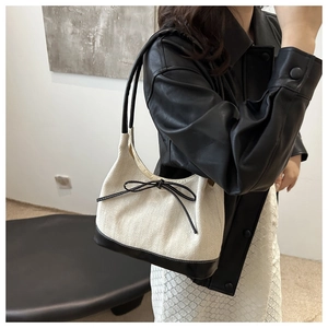 Detail of canvas tote with black leather trim and bow knot on a minimalist handbag