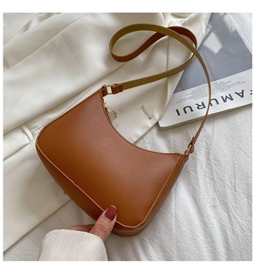 Close-up of caramel leather underarm bag with litchi texture and gold hardware details
