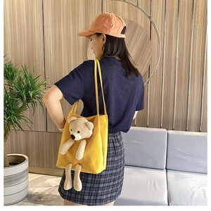 Detail of yellow canvas tote bag with 3D plush bear on model in cozy interior setting