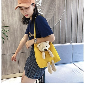Detail of yellow canvas crossbody bag featuring a 3D teddy bear plush doll ornament