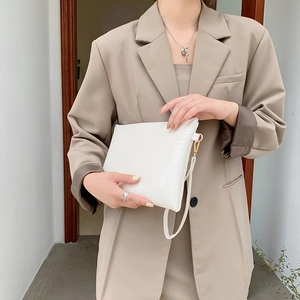 Elegante pochette a busta bianca con trama a coccodrillo portata da modella in tailleur