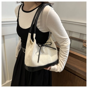 Detail of herringbone weave tote bag with black leather trim and delicate ribbon bow