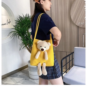 Yellow canvas tote bag with 3D teddy bear plush detail shown on a model
