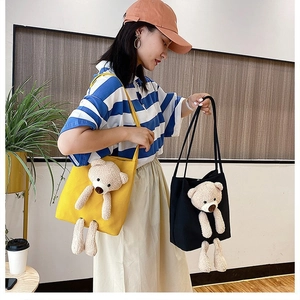 Close-up of canvas tote bag featuring a 3D plush bear ornament in indoor setting