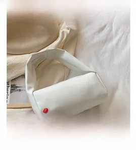 Close-up of a minimalist white matte leather handbag featuring smooth seamless handle detail