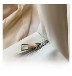 Close-up of smooth silver zipper hardware and stitching on cream faux leather handbag