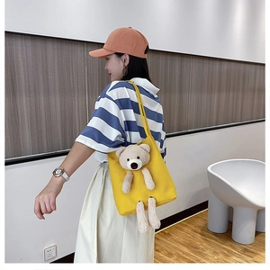 Close-up of yellow canvas shoulder bag with 3D plush bear and dual strap detail