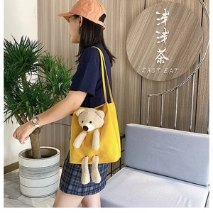 Detail of yellow canvas tote bag with a 3D plush bear decorative doll attachment