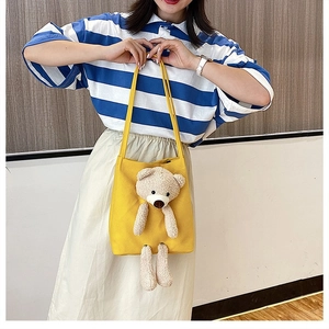 Detail of a bright yellow canvas tote bag featuring a cute 3D plush bear decorative doll