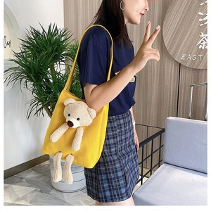 Detailed view of a yellow canvas bag featuring a cute 3D plush bear on model