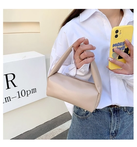 Detail of minimalist beige handbag with unique knotted handle and smooth leather texture