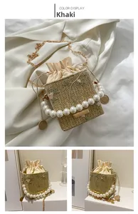Detail of woven straw bucket bag with floral embroidery and pearl handle strap