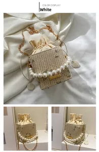 Detailed white straw bucket bag with floral embroidery and elegant pearl handle