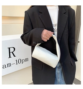 Minimalist white cylinder handbag in high-quality textured leather held by a model